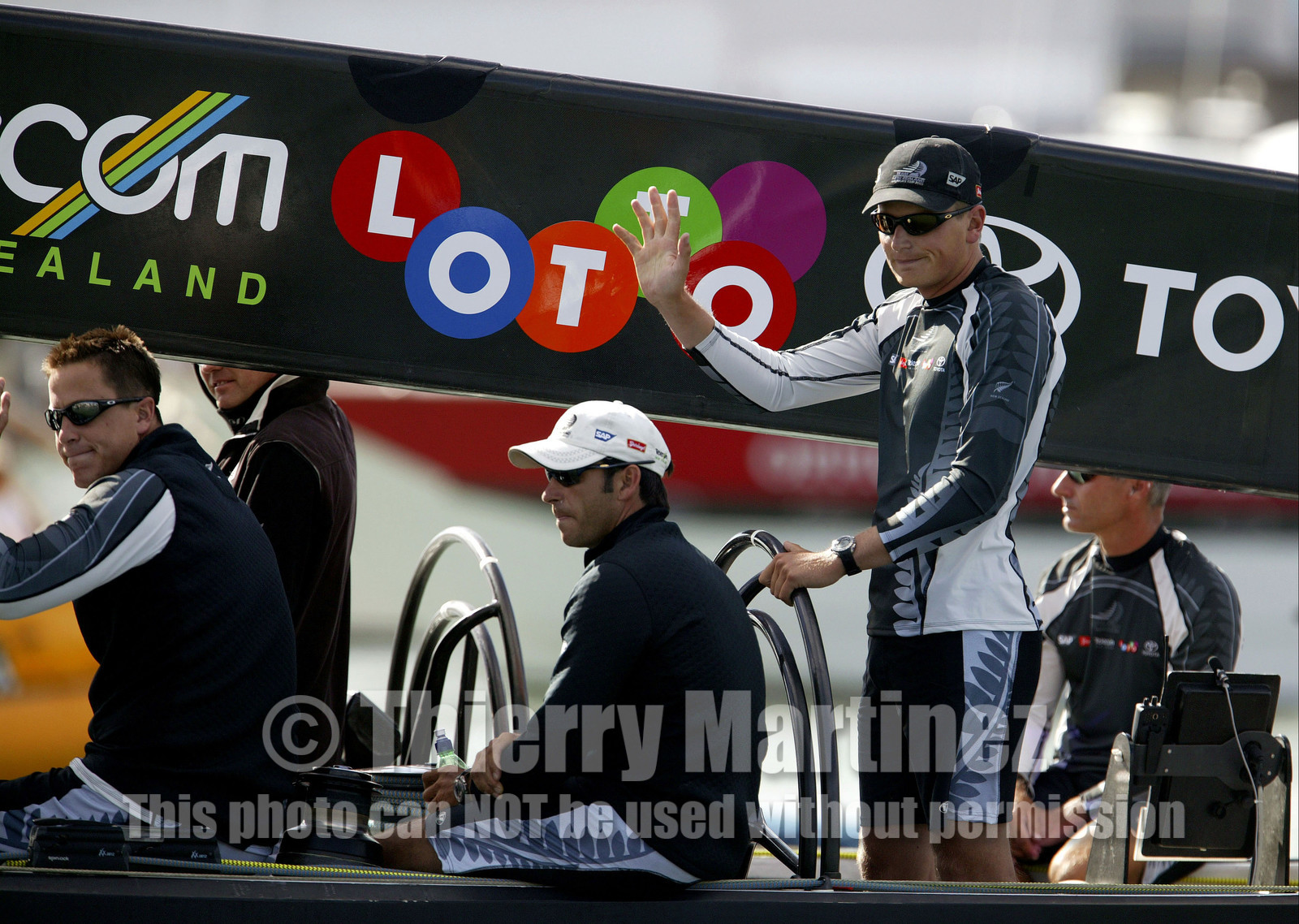 03_0149D ©Th.Martinez - Auckland (NZ) . America's Cup 2003. 15th February 2003. Day 1..Team NZ  NZL 82 leaving Vidauct Harbour to defend 31st America's cup against Challenger Team Alinghi in first race..Dean Barker Team NZ 's skipper at the helm and Hamish Pepper  , tactician, next to him waving to Team NZ fans.