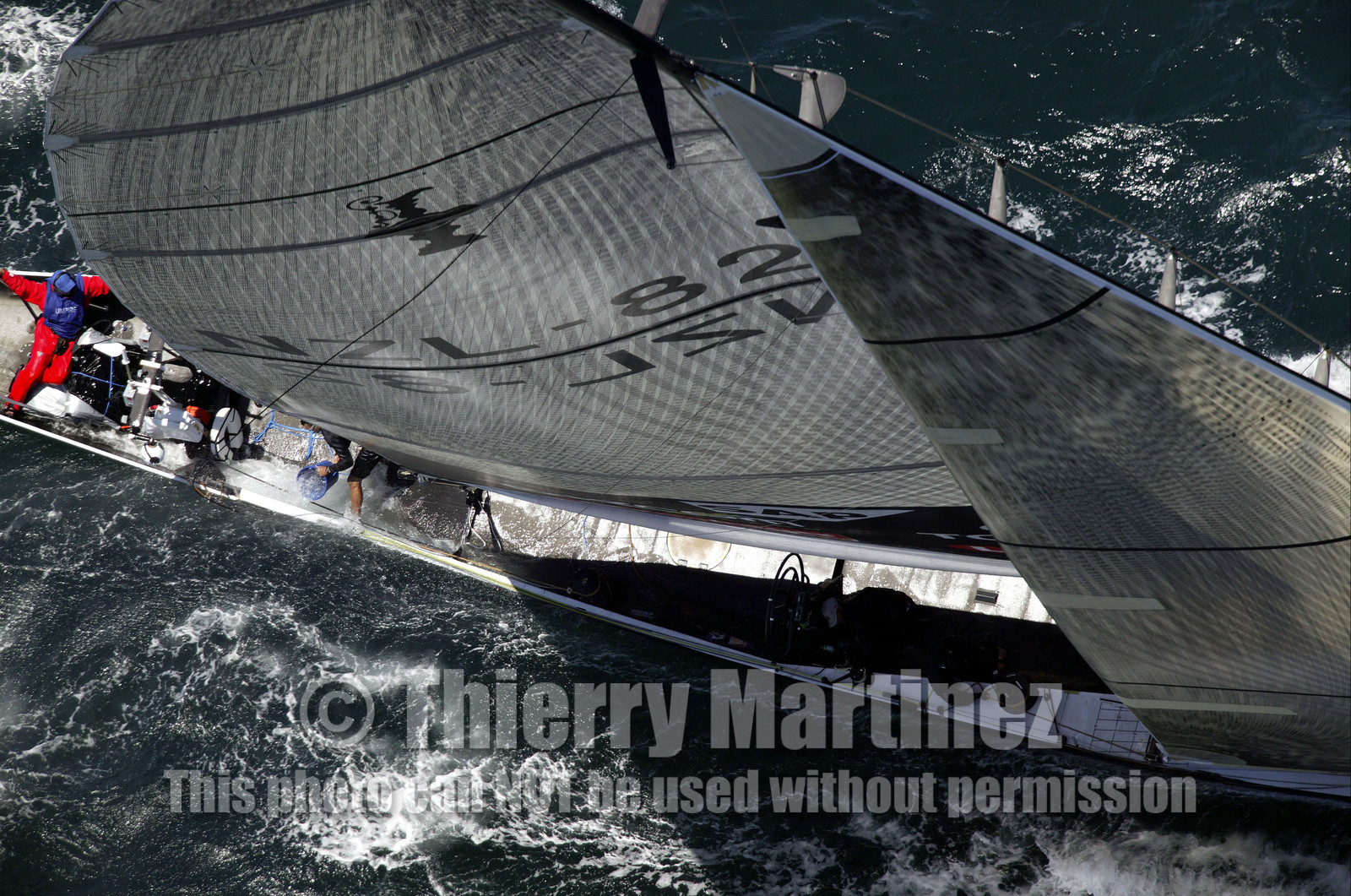 03_0167D ©Th.Martinez - Auckland (NZ) . America's Cup 2003. 15th February 2003. Day 1..Alinghi (SUI 64) vs Team NZ (NZL 82) .NZL 82 in first minutes of Race 1 before retiring on damage. .Matt Mitchell (Team NZ midbowman) bailing water out of NZL 82. .
